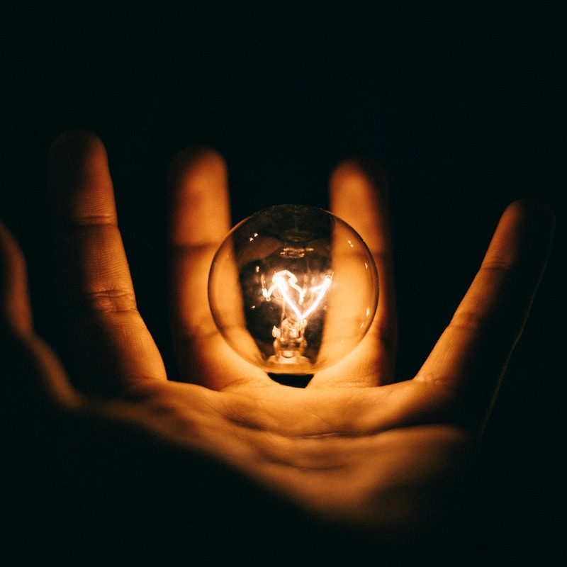 clear glass bulb on human palm